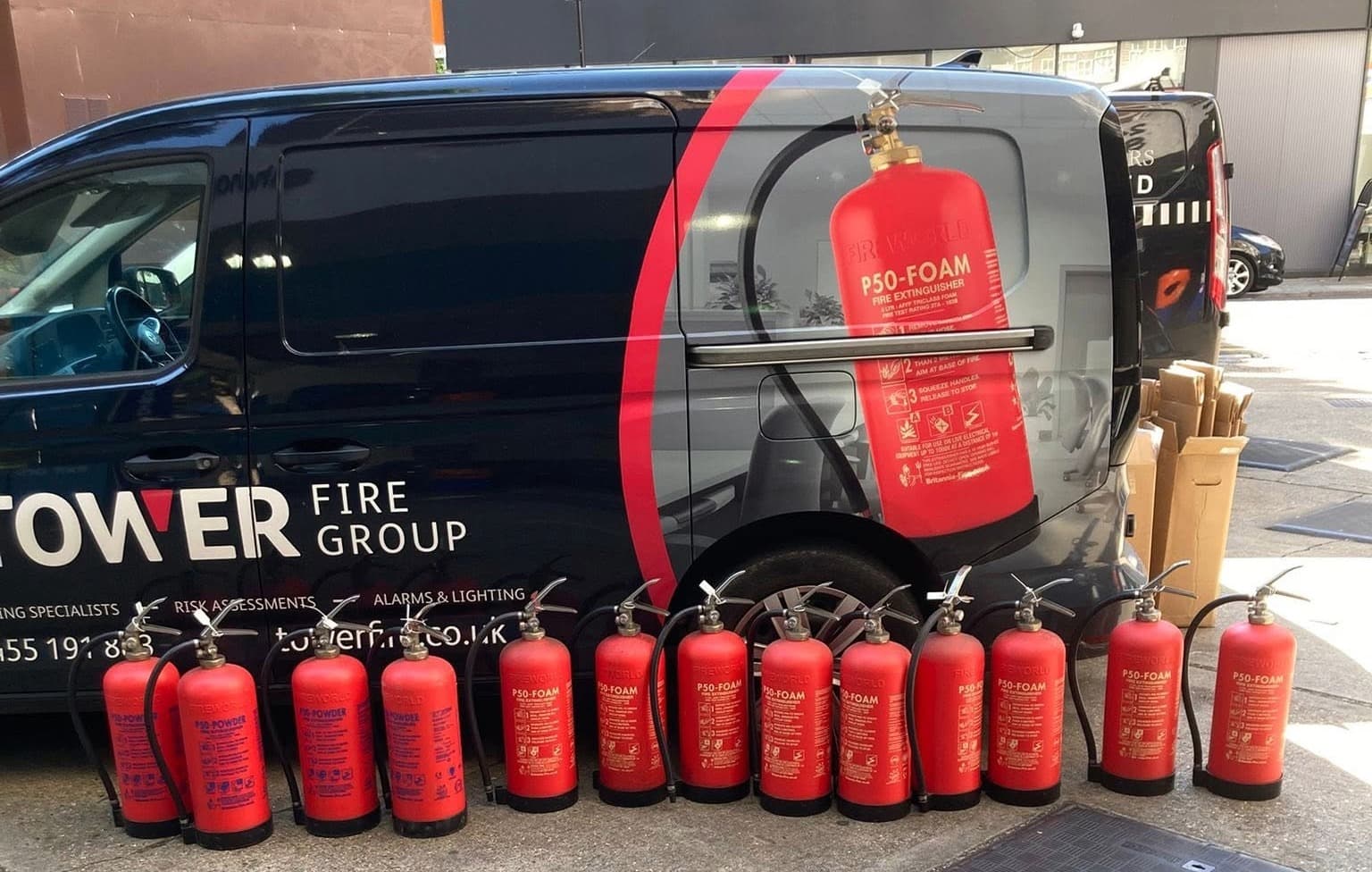 A Towerfire van with a row of serviced extinguishers lined up beside it